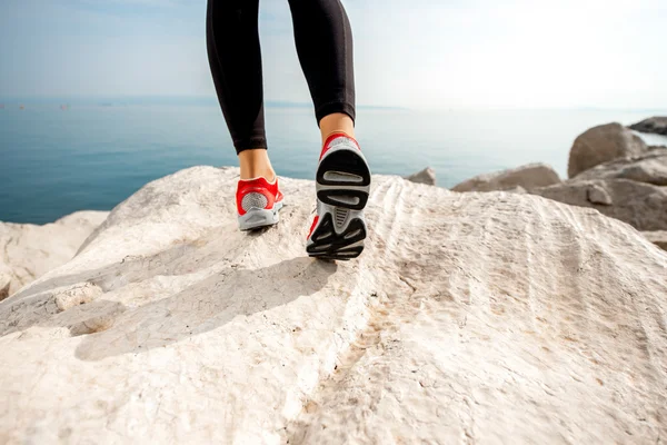 Sporty woman legs on the rocky beach — Stock Photo, Image