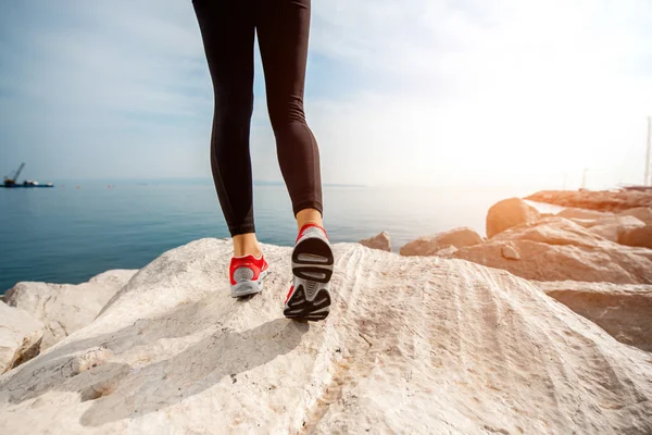 Sporty woman legs on the rocky beach — Stock Photo, Image