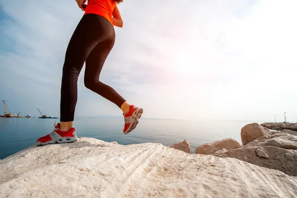 Sportowe kobieta działa na kamienistej plaży — Zdjęcie stockowe