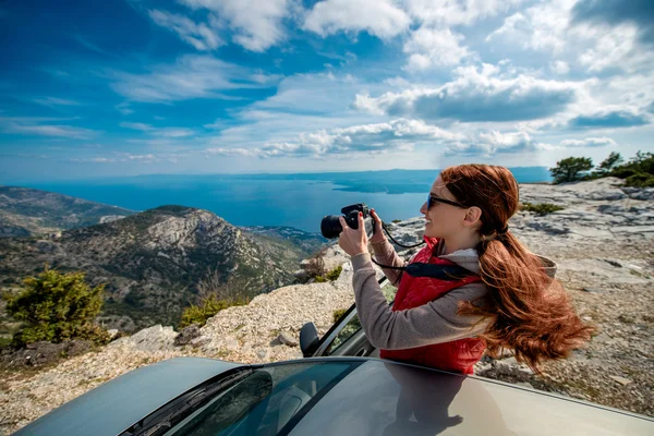 Kobieta fotograf z samochodu na szczycie góry — Zdjęcie stockowe