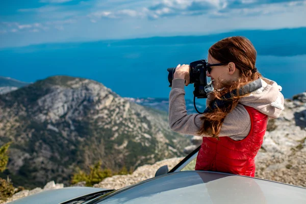 ผู้หญิงช่างภาพที่มีรถอยู่บนยอดภูเขา — ภาพถ่ายสต็อก