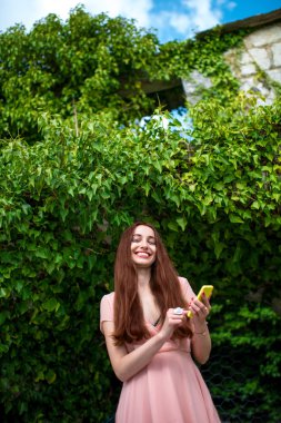 Yeşil sarmaşık arka plan üzerinde telefon kullanan kadın