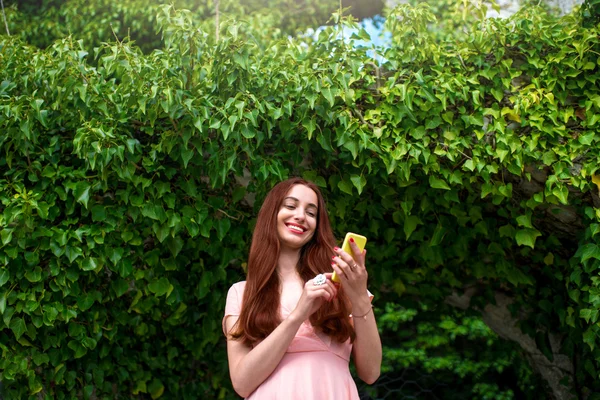 Mujer usando teléfono sobre fondo de hiedra verde — Foto de Stock