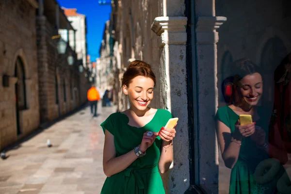 Woman with mobile phone in old city street — Stock Photo, Image