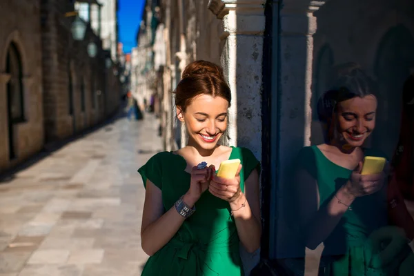 Vrouw met mobiele telefoon in de oude stad straat — Stockfoto