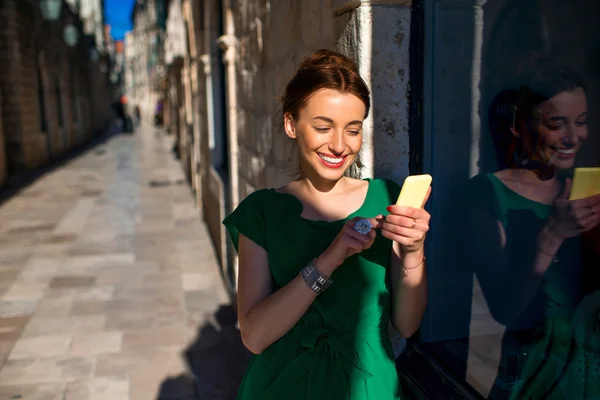 Kobieta z telefonem komórkowym w starego miasta ulica — Zdjęcie stockowe