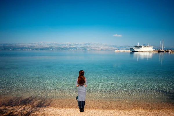Mujer mirando ferry en la playa —  Fotos de Stock