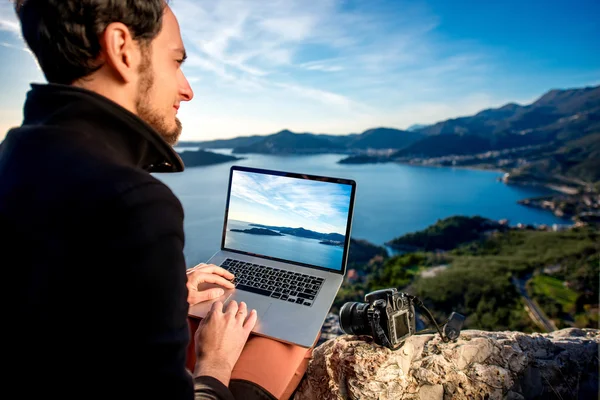 Uomo con computer portatile in cima alla montagna — Foto Stock