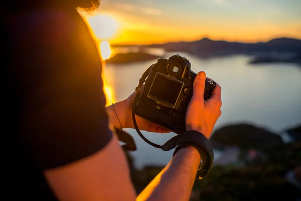 Hombre fotografiando la puesta de sol en la cima de la montaña —  Fotos de Stock