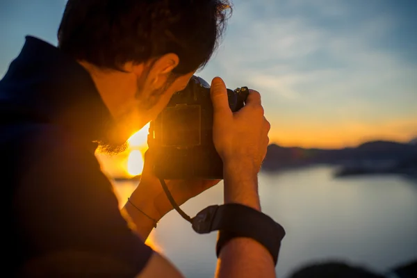 Чоловік фотографує захід сонця на вершині гори — стокове фото