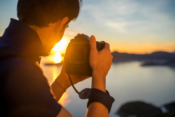 Hombre fotografiando la puesta de sol en la cima de la montaña — Foto de Stock