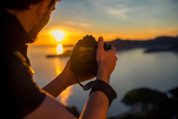 Homem fotografando o pôr do sol no topo da montanha — Fotografia de Stock