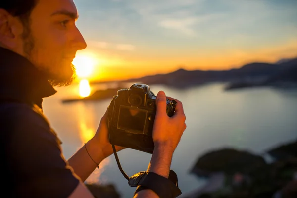 Homem fotografando o pôr do sol no topo da montanha — Fotografia de Stock