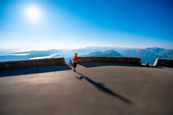 Mulher correndo na estrada da montanha — Fotografia de Stock