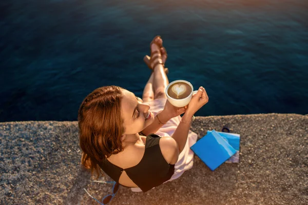 Young woman sitting on the pier at sunrise — Stock Photo, Image