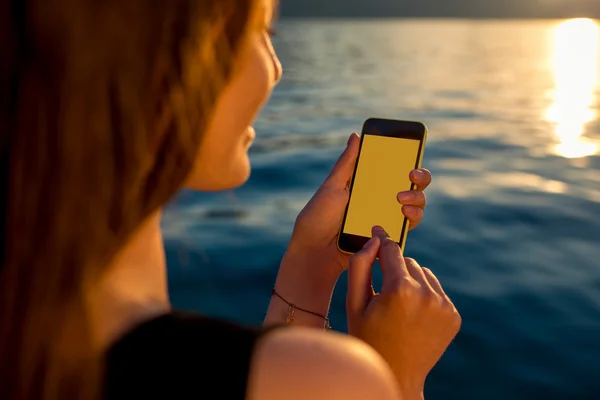 Güneş doğarken telefon kullanan genç kadın — Stok fotoğraf