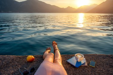 Womans legs on the pier at sunset clipart