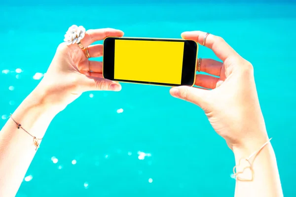 Trzymając telefon na tle morza — Zdjęcie stockowe