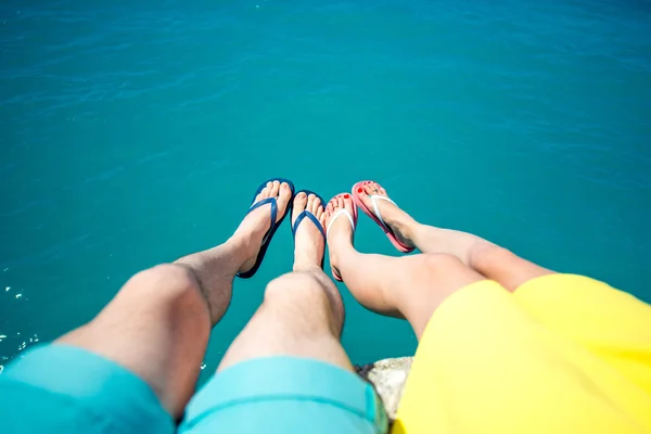 Paren benen in slippers op de achtergrond van de zee — Stockfoto