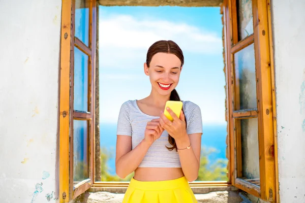 Frau benutzt Handy in der Nähe des Fensters — Stockfoto