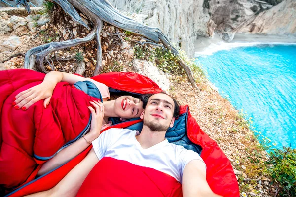 Jovem casal em sacos de dormir perto do mar — Fotografia de Stock