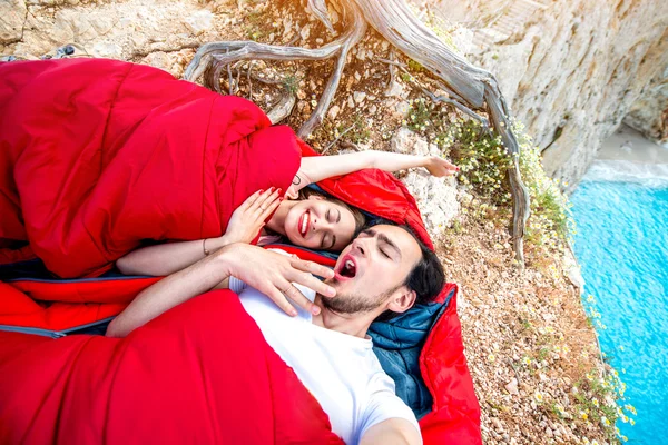 Young couple in sleeping bags near the sea — Stock Photo, Image