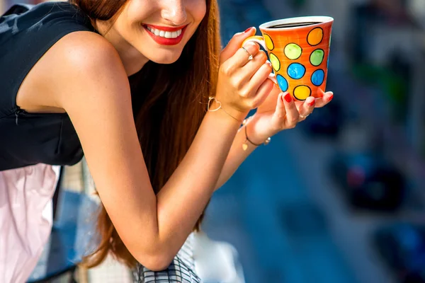 Женщина с красочной чашкой кофе на балконе — стоковое фото