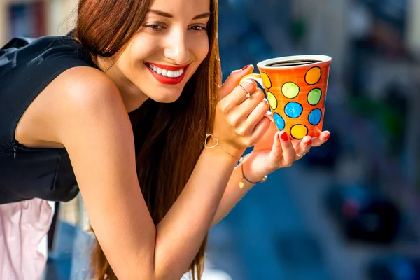 バルコニーの上にカラフルなコーヒー カップを持つ女性 — ストック写真