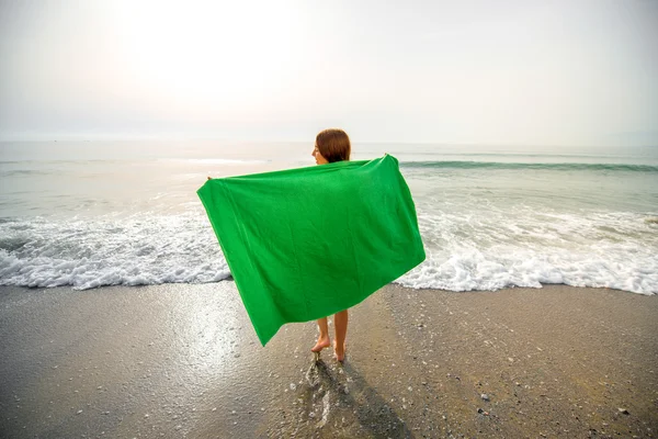 Женщина в зеленом полотенце на пляже — стоковое фото