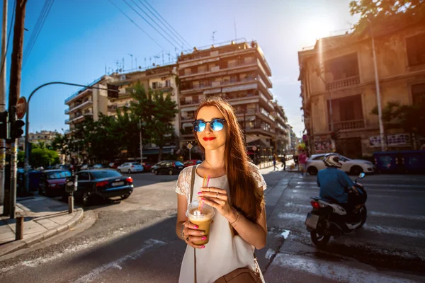 Женщина ходит по улице с кофе на вынос — стоковое фото