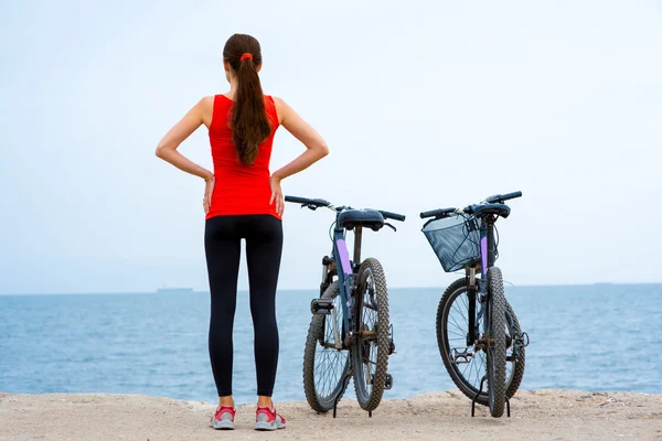 Sport woman with bicycles on the beach — Stock Photo, Image