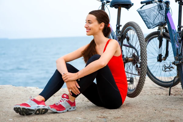 Sport vrouw met fietsen op het strand — Stockfoto