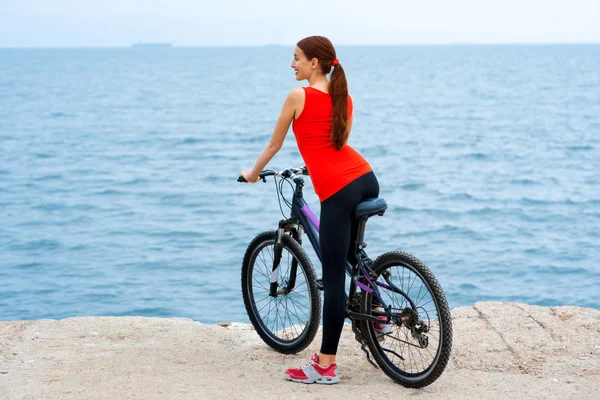 Γυναίκα του αθλητισμού με τα ποδήλατα στην παραλία — Φωτογραφία Αρχείου