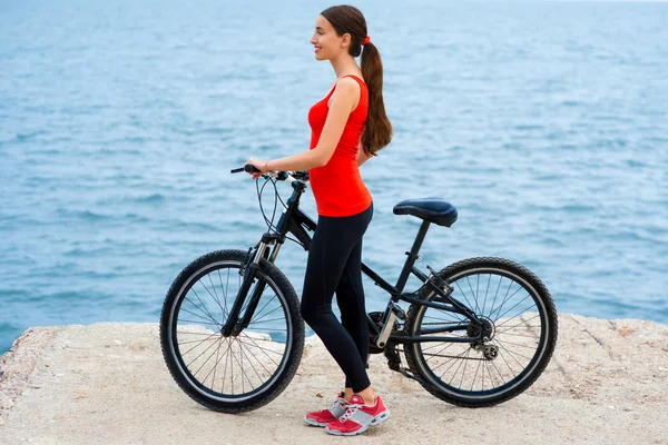 Mulher do esporte com bicicletas na praia — Fotografia de Stock