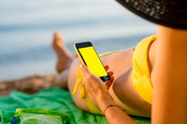 Sahilde cep telefonu kullanan kadın