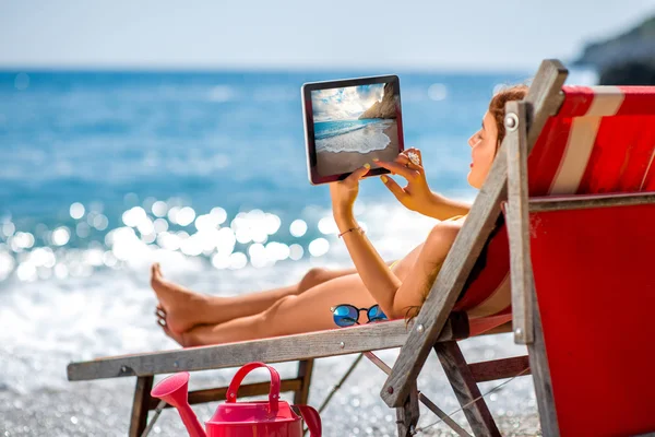 Woman looking photos with tablet on the sunbed — Stockfoto