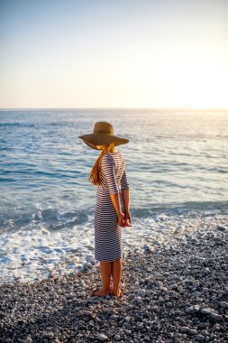 Woman in stripped dress with a hat on the beach
