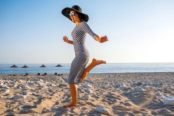 Woman in stripped dress with a hat on the beach — Stockfoto