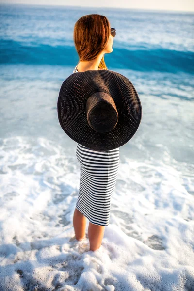 Woman in stripped dress with a hat on the beach — Stock Photo, Image