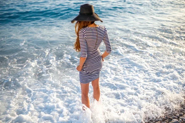 Frau in entkleidetem Kleid mit Hut am Strand — Stockfoto