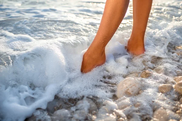 Womans legs on the stone beach with water — Stock Photo, Image