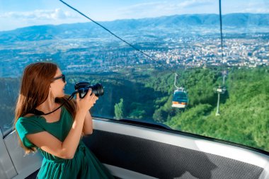 Woman in cable car with cityscape view