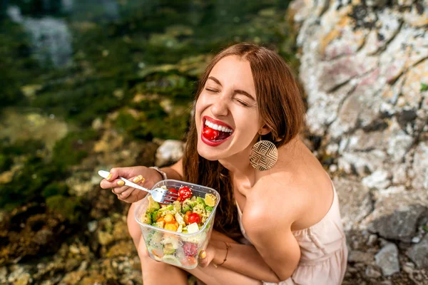 Woman eating healthy salad near the river — Stock fotografie