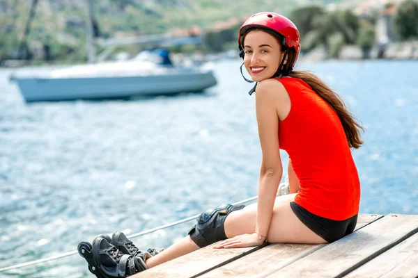 Frau in Sportbekleidung mit Rollschuhen auf der Seebrücke — Stockfoto