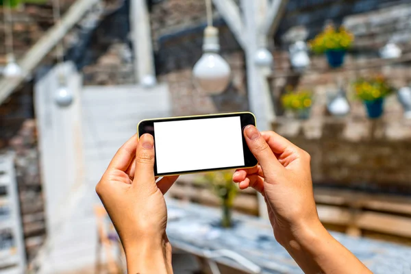 Tenere il telefono su sfondo interno bianco — Foto Stock