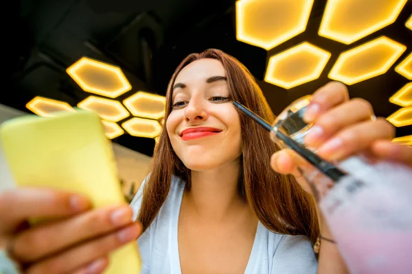 Žena s telefonem a nápoj v moderním interiéru — Stock fotografie