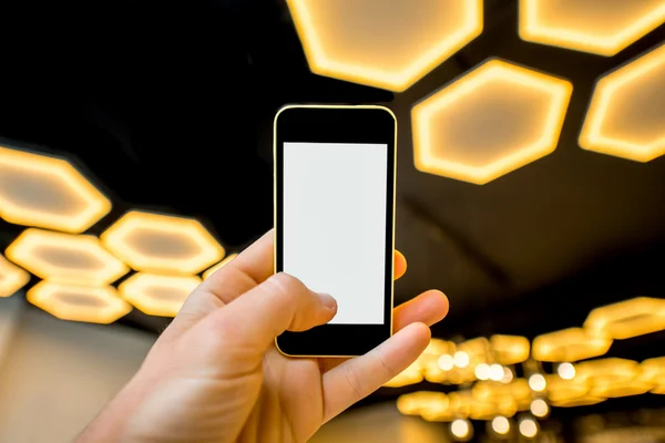 Segurando telefone no fundo de luz moderna — Fotografia de Stock