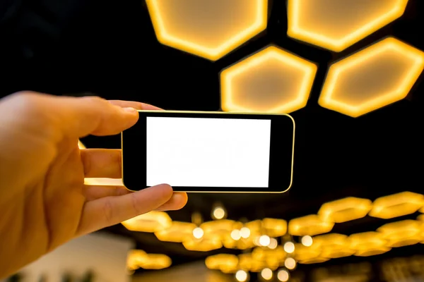Segurando telefone no fundo de luz moderna — Fotografia de Stock