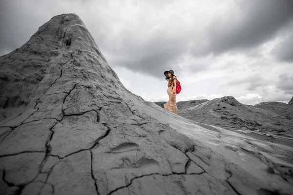 Женщина-путешественница, идущая рядом с грязевыми вулканами — стоковое фото