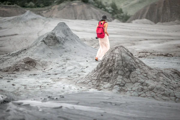 Женщина-путешественница, идущая рядом с грязевыми вулканами — стоковое фото